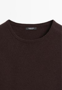 Bruine gebreide trui met een ronde halslijn, voorzien van een geribde afwerking. De stof lijkt zacht en glad, met een label waarop "Massimo Dutti" staat.