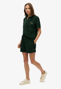 Camisa de algodón verde de manga corta con bolsillo, combinada con pantalones cortos a juego. Patrón texturizado, cintura elástica y detalle de logotipo bordado.