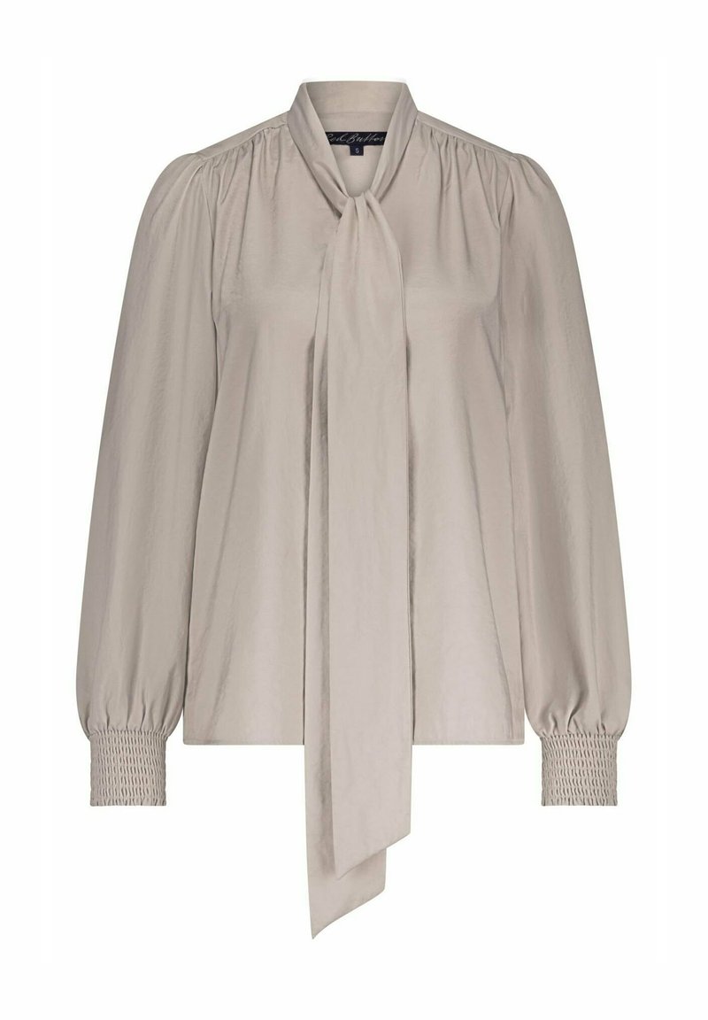 Silky beige blouse with long puff sleeves, tie-neck detail, and smocked cuffs; features a smooth texture and relaxed fit.