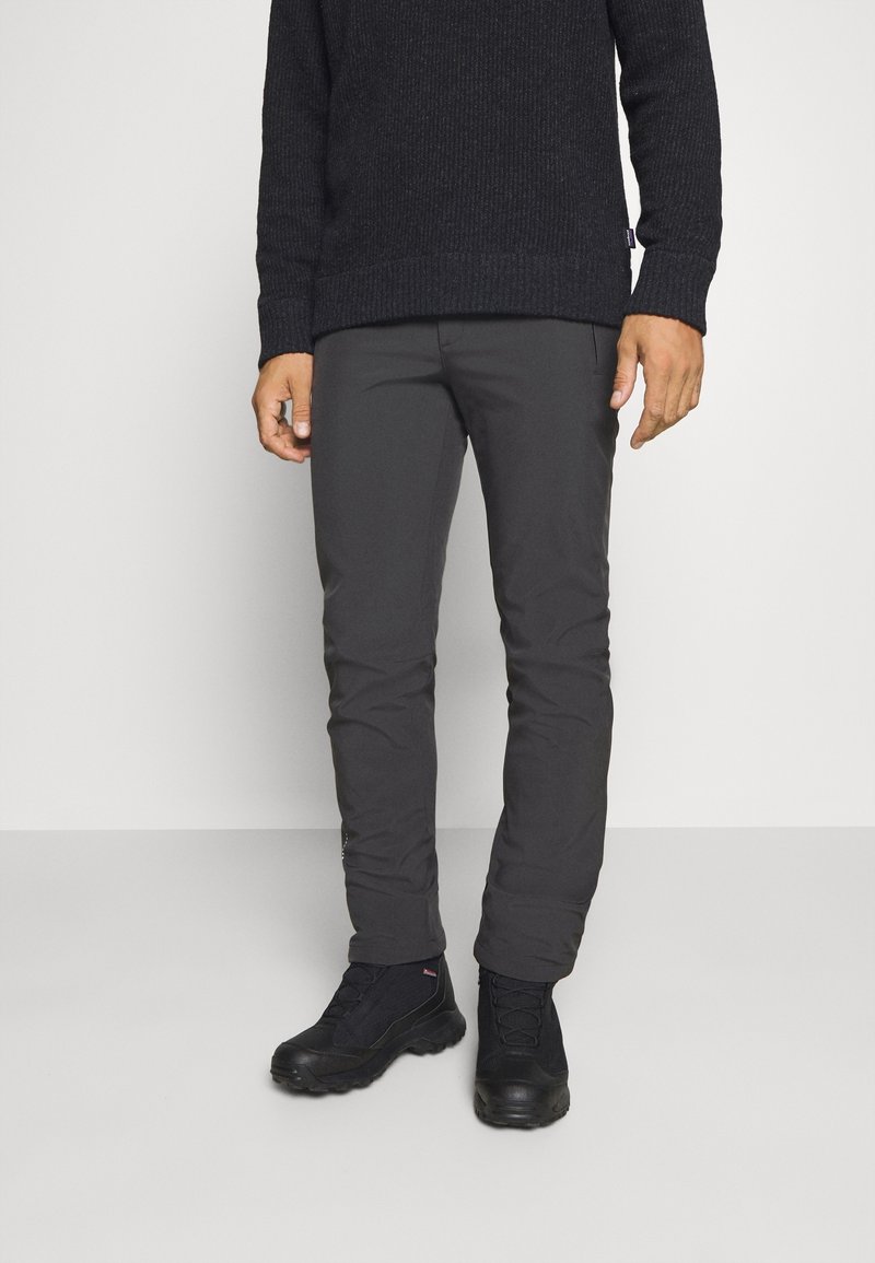 Pantalons slim gris foncé, fabriqués à partir d'un matériau léger et flexible. Associés à des bottes de randonnée noires, avec une surface texturée et des détails en dentelle.