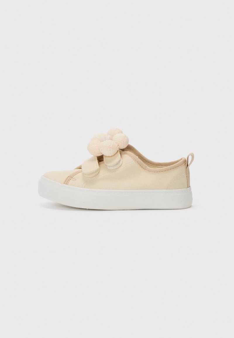 Hellbeige Leinenschuhe mit runder Zehenpartie, weißer Gummisohle und strukturierten, gepolsterten Akzenten auf der Vorderseite. Mit einer Schlaufe zum Anziehen auf der Rückseite.