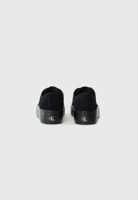 Sneakers in suede nero con suole in gomma, punta arrotondata e retro rialzato. Presentano un dettaglio logo sul lato e un design minimalista.