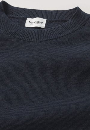 Marineblauer gestrickter Pullover mit rippenförmigem Rundhalsausschnitt und weicher Textur. Das Etikett trägt die Aufschrift "hessnatur", die die Marke und Pflegeanweisungen angibt.