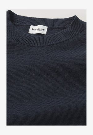 Marineblauer gestrickter Pullover mit rippenförmigem Rundhalsausschnitt und weicher Textur. Das Etikett trägt die Aufschrift "hessnatur", die die Marke und Pflegeanweisungen angibt.