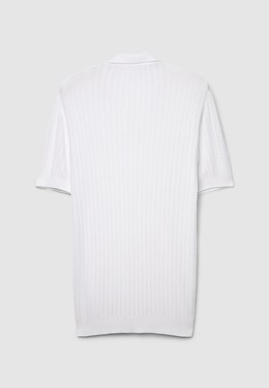 Polo blanc à manches courtes, présentant une texture côtelée, un col standard et un motif de tricot subtil, offrant un design épuré et minimaliste.