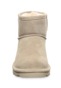 Beige Wildleder-Stiefelette mit runder Zehenpartie, sichtbaren Nähten und weichem, crèmefarbenem Schaffellfutter im Inneren.