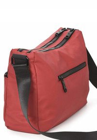 Bolso bandolera de tela roja con un acabado texturizado, que cuenta con dos cremalleras superiores, un bolsillo frontal con cremallera y una correa negra ajustable.