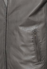 Szara skórzana kurtka o gładkiej fakturze, z zamkiem błyskawicznym z przodu i boczną kieszenią na zamek dla zwiększonej funkcjonalności.