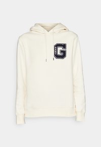 Sudadera con capucha color crema hecha de tela suave, con un gran logo "GANT" bordado en azul marino en el frente, con cuerdas ajustables.