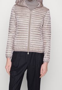 Beige gewatteerde jas met een capuchon, voorzien van een ritsluiting en een horizontaal gestikte patroon. Zachte textuur en elastische manchetten.