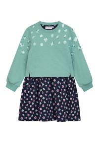 Mintgrüner Sweatshirt mit dekorativen Pailletten, kombiniert mit einem navyfarbenen Rock mit einem mehrfarbigen, abstrakten Punktmuster.