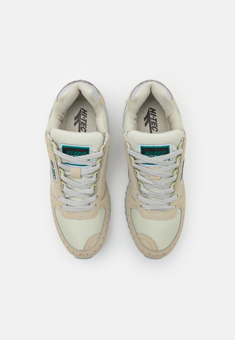 Beżowe i szare sneakersy z teksturowaną cholewką, dopasowanymi sznurowadłami i zielonym logo. Posiadają amortyzowaną podeszwę oraz zaokrąglony czubek.