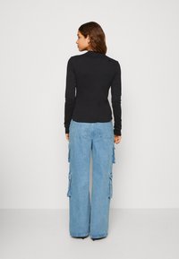 Top nero a maniche lunghe e pantaloni cargo larghi azzurri chiaro con tasche laterali, caratterizzati da un fit rilassato e una morbida texture del tessuto.