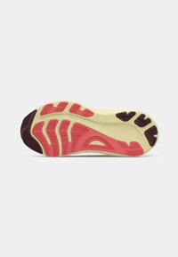 Semelle de chaussure en caoutchouc avec une base jaune, des accents rouges texturés et des sections violettes foncées. Le motif de la semelle offre adhérence et soutien.
