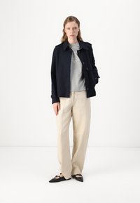 Navy cotton jacket with button closure, gray shirt, beige wide-leg trousers, and black pointed flats. Simple design with no visible patterns.