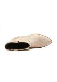 Botín de ante beige con punta afilada, costura decorativa y cremallera lateral. Textura suave con color de suela contrastante.