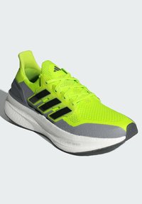 Neon žute atletske tenisice s sivim naglascima, mrežasti gornji dio i crne pruge. Imaju udoban bijeli potplat označen "LIGHTBOOST".