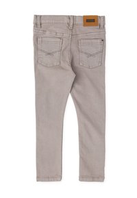 Jeans skinny de mezclilla gris con dos bolsillos traseros, detalles de costura visibles y una etiqueta de parche de cuero marrón en la cintura. Textura suave en toda su superficie.