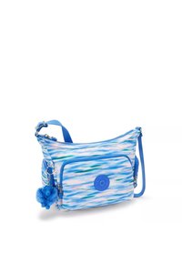 Blå crossover taske lavet af mønstret stof med bølger af lys og mørk blå. Har en frontlomme med lynlås og en blå pom-pom charm.