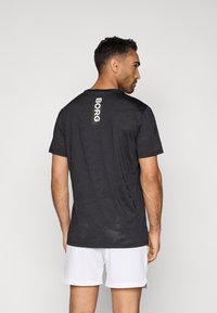 Μαύρο αθλητικό T-shirt με καμουφλάζ μοτίβο και λευκό λογότυπο "BORG" στην πλάτη. Κοντά μανίκια και στρογγυλή λαιμόκοψη. Ελαφρύ ύφασμα.