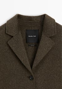 Cappotto in misto lana verde scuro con finitura texture, dotato di colletto a punte e chiusura a un bottone, etichettato "Massimo Dutti."