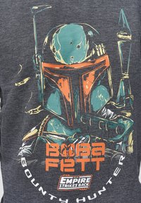 Camiseta gris con un gráfico colorido de Boba Fett, un personaje enmascarado de Star Wars, con texto y detalles de diseño en naranja y azul verdoso.