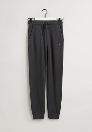 Ciemnoszare spodnie dresowe z elastycznymi mankietami, bocznymi kieszeniami, ściągaczem w pasie i małym białym logo GANT na górnej części nogawki, zawieszone na białym wieszaku.