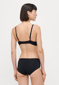 Black bikini set featuring a back closure and adjustable straps. The material is smooth with minimal detailing and a classic fit.