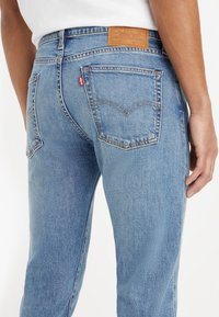 Ljusblå denimjeans med rak passform, utrustad med en läderbaklapp, två bakfickor och subtila blekningsdetaljer.