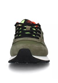 Scarpa sportiva verde in suede con lacci neri, dettagli in verde neon e una suola in gomma nera a contrasto. Logo iconico sulla linguetta.