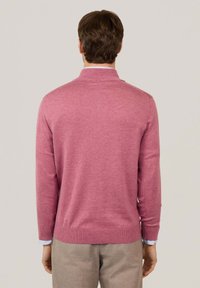 Maglione a maglia rosa chiaro con colletto. Presenta maniche lunghe, polsini arricciati e orlo. Texture liscia senza fantasie.