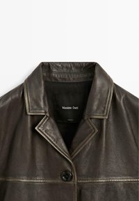 Giacca in pelle marrone scuro con ampio colletto, un singolo bottone visibile e etichetta "Massimo Dutti" all'interno del colletto.