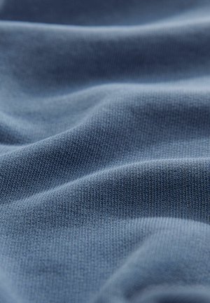 Soft, blue fabric with a textured, ribbed pattern. The material appears lightweight and slightly crinkled, emphasizing its pliability.