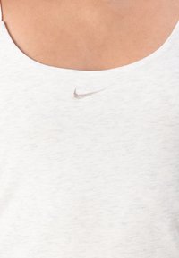 Camisola de alças branca de algodão com decote em forma de coração e um pequeno logo da Nike em prata no centro, confeccionada em um tecido suave e texturizado.