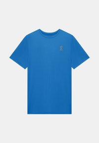 T-shirt bleu manches courtes avec col rond et petit logo gris sur la partie supérieure gauche de la poitrine, présenté sur un fond gris clair uni.