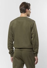 Olivengrønn genser med rund hals, lange ermer, ribbestrikkede mansjetter og kant, glatt tekstur, vist bakfra, kombinert med matchende bukser.