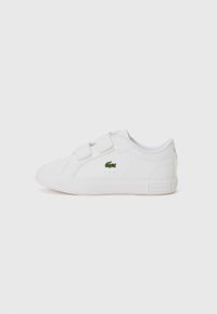 Baskets blanches avec une texture en cuir lisse, deux bandes auto-agrippantes et un petit logo Lacoste vert sur le côté. Design minimaliste.