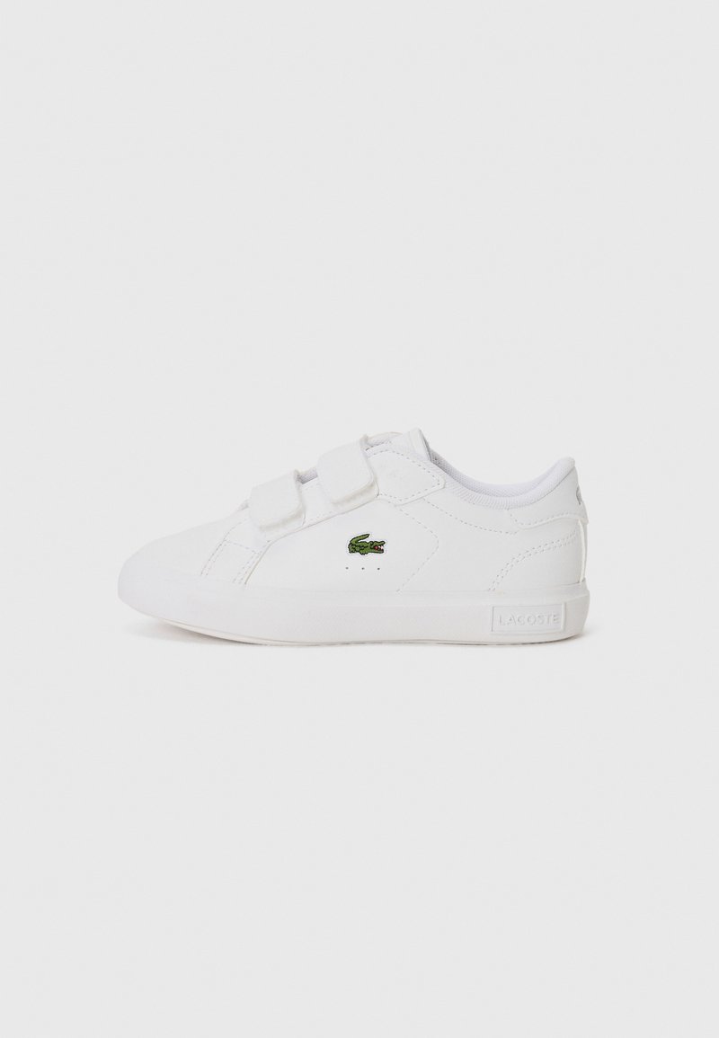 Baskets blanches avec une texture en cuir lisse, deux bandes auto-agrippantes et un petit logo Lacoste vert sur le côté. Design minimaliste.