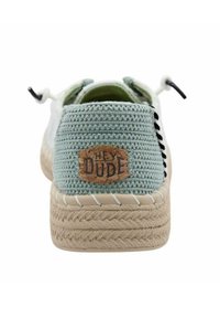 Scarpe slip-on di colore verde chiaro intrecciate, con una superficie texturizzata, punta rotonda, suola in fibra naturale e un'etichetta in sughero che legge "HEY DUDE" sul tallone.