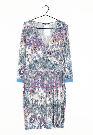Vestido envolvente con estampado floral y mangas largas, que presenta una mezcla de tonos azules, rojos y beige, elaborado con un tejido ligero. Colgado de un gancho negro.