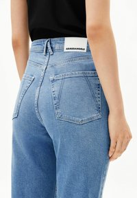 Lichtblauwe denim jeans met een hoge taille, voorzien van twee achterzakken en een label op de tailleband. Soepele textuur met een klassiek ontwerp.