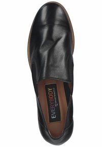 Chaussure en cuir noir à enfiler, avec une texture lisse, un bout rond, des accents élastiques sur les côtés et une semelle en caoutchouc brun. Présente une étiquette de marque colorée.