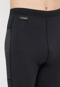 Juodos sportinės legging kelnes su tekstūruota, drėgmę išskiriančia medžiaga. Su plokščiais siūlais ir tinkleliu ant juosmens su Polartec logotipo detale.
