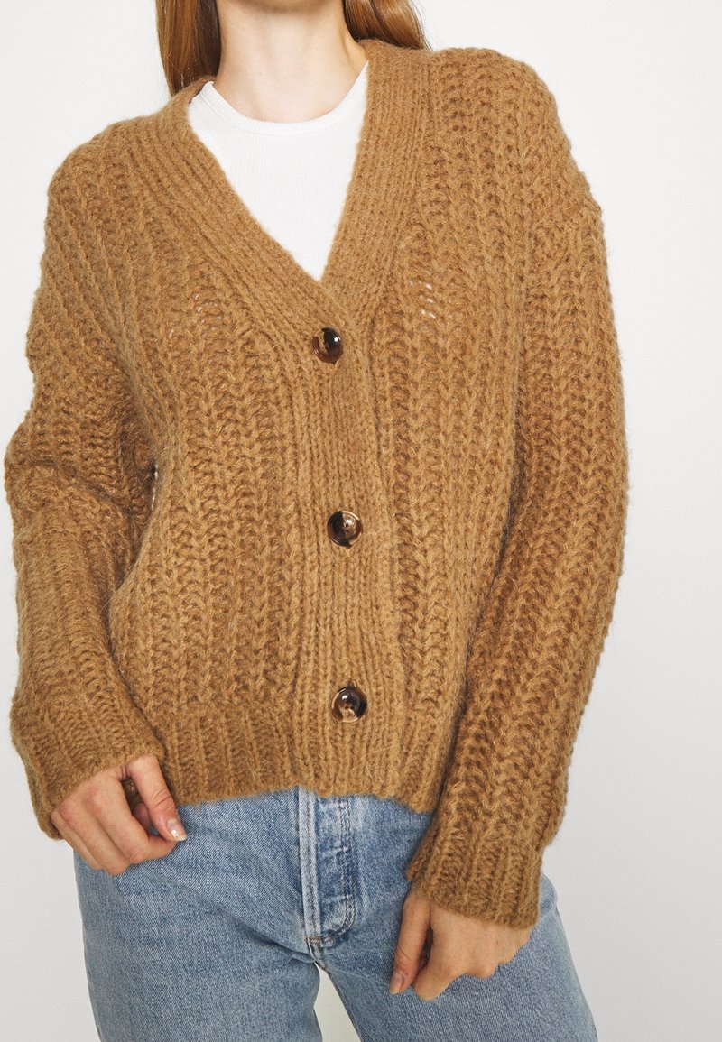 Brauner Strickcardigan mit V-Ausschnitt, ausgestattet mit drei großen dunklen Knöpfen, gerippten Bündchen und lockerer Passform. Strukturmuster im gesamten Kleidungsstück.