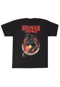 Černé bavlněné tričko s logem "Stranger Things" v červené barvě. Na zadní straně je ilustrace stvoření na ohnivě oranžovém pozadí.