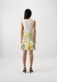Pletený top v odtieňoch off-white s výstrihom do U, kombinovaný s plisovanou kvetinovou sukňou v pastelových farbách, ktorá má volány na spodnom leme.