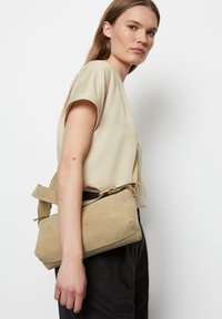 Beige Wildlederhandtasche in rechteckiger Form, mit einem kurzen Trageriemen und goldenen Hardware-Elementen. Glatte Textur, minimalistisches Design.
