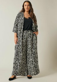 Zwart-wit gestippeld kimono-set, met wijde broekspijpen en een zwarte top met kantafwerking, gemaakt van lichtgewicht stof.