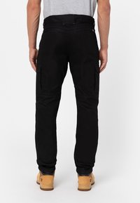 Black cargo pants made of durable material, featuring side pockets, a straight leg design, and reinforced stitching at the knees.