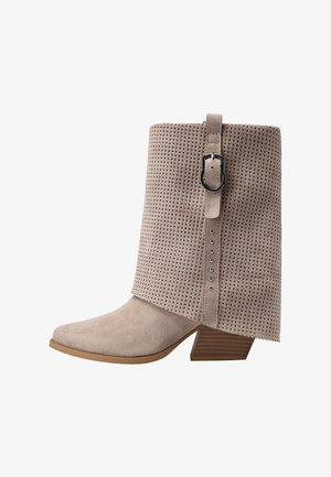 Bottine en daim taupe avec un col perforé, une bride décorative avec boucle, et un talon bloc empilé en bois.